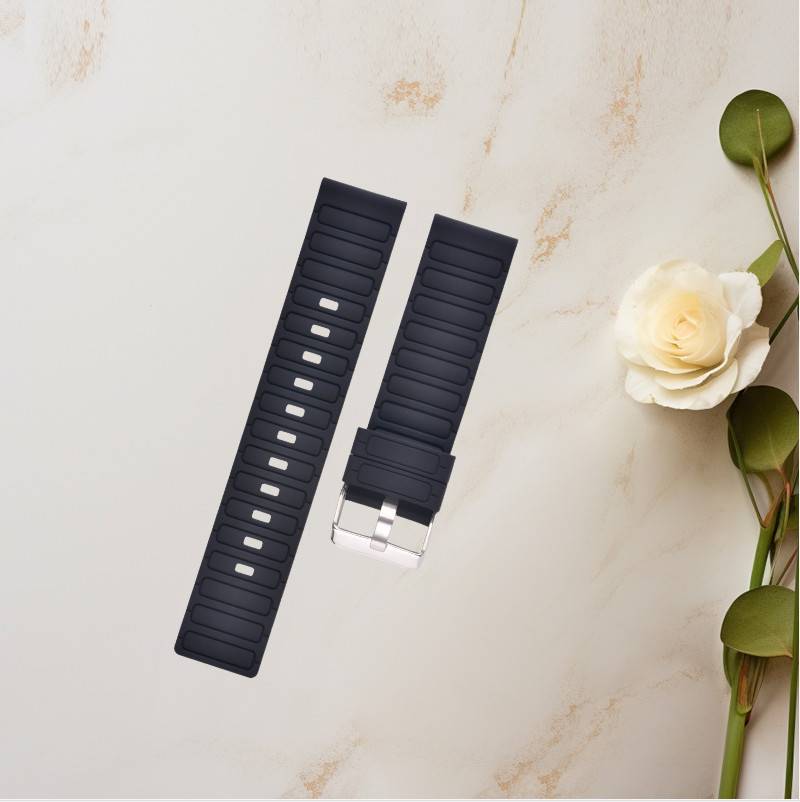 Zwei schwarze Silikonuhrenarmbänder, eines mit einer silbernen Schließe, auf einer hellen Marmoroberfläche neben einer weißen Blume und grünem Stiel ausgestellt.