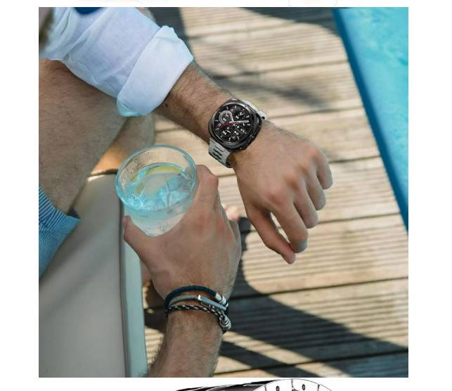 Zwei Männer entspannen sich neben einem Pool oder einer Terrasse, einer hält ein Getränk in der Hand und der andere schaut auf seine Armbanduhr.