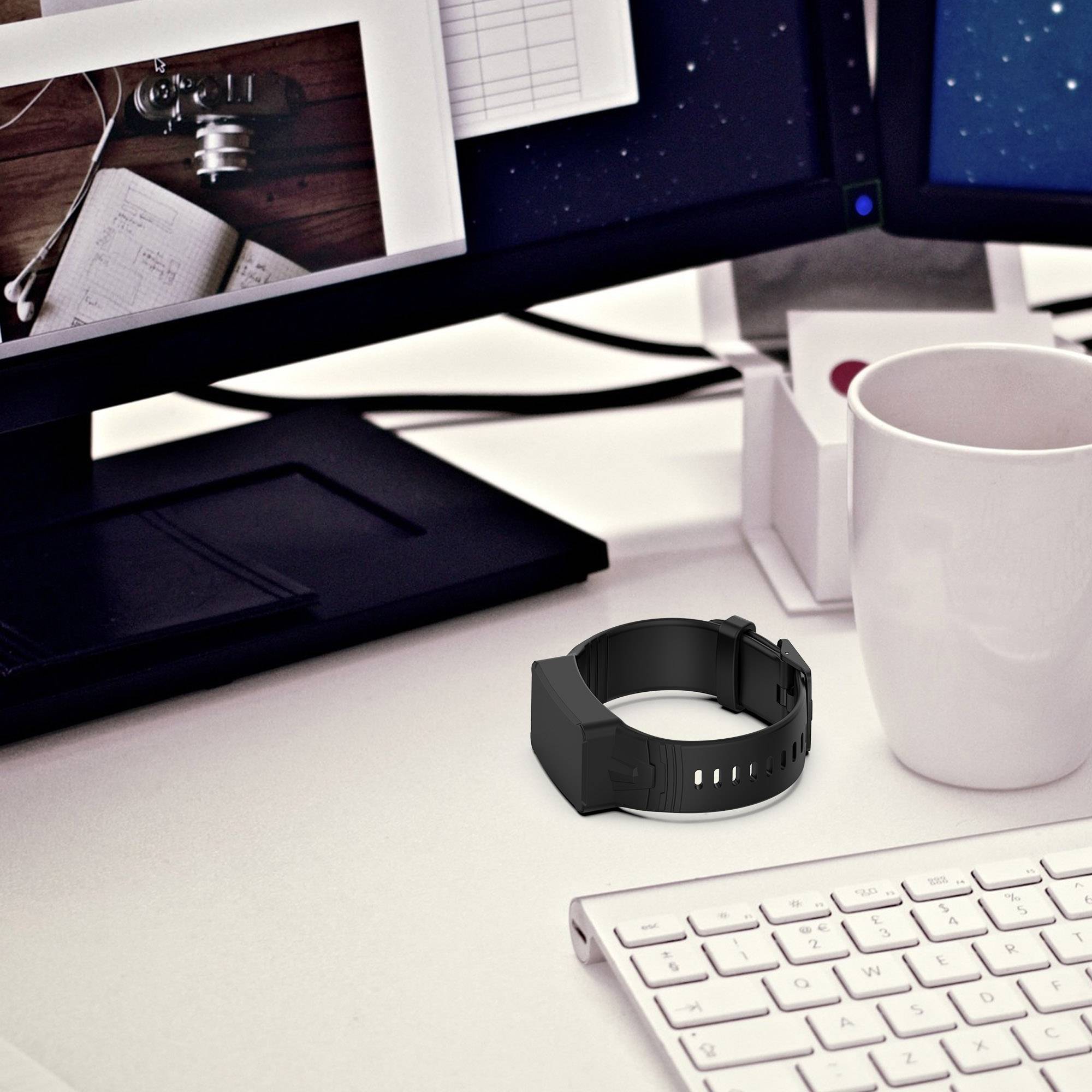 Schreibtischarbeitsplatz mit Computermonitor, Tastatur, schwarzem Smartwatch-Armband, weißem Becher, Notizbuch und Schreibwaren auf einer weißen Tischplatte.