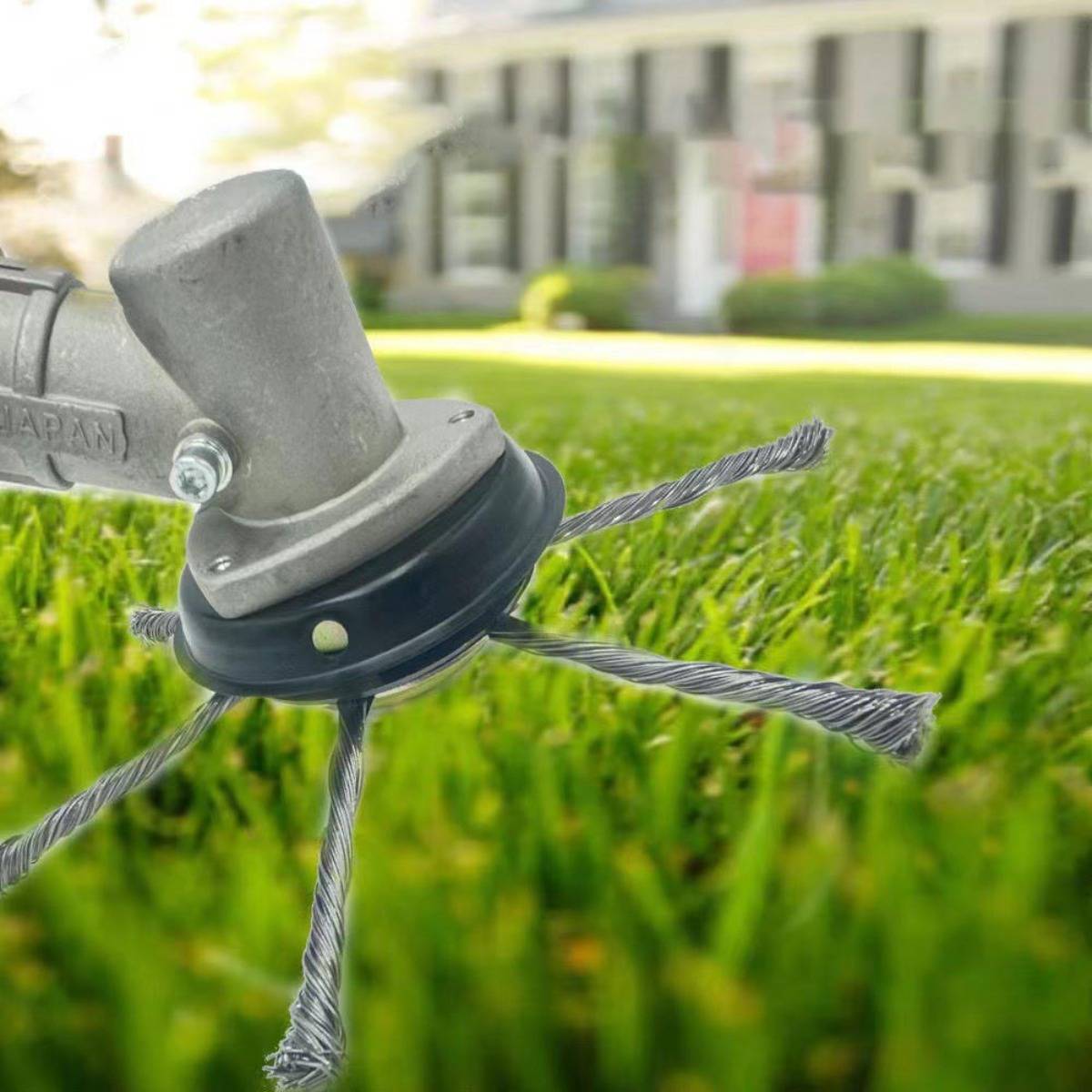 Nahaufnahme eines Trimmer-Kopfes mit Metalldrähten über grünem Gras, das ein Hofwerkzeug zeigt, das Vegetation in einem Wohngebiet schneidet.