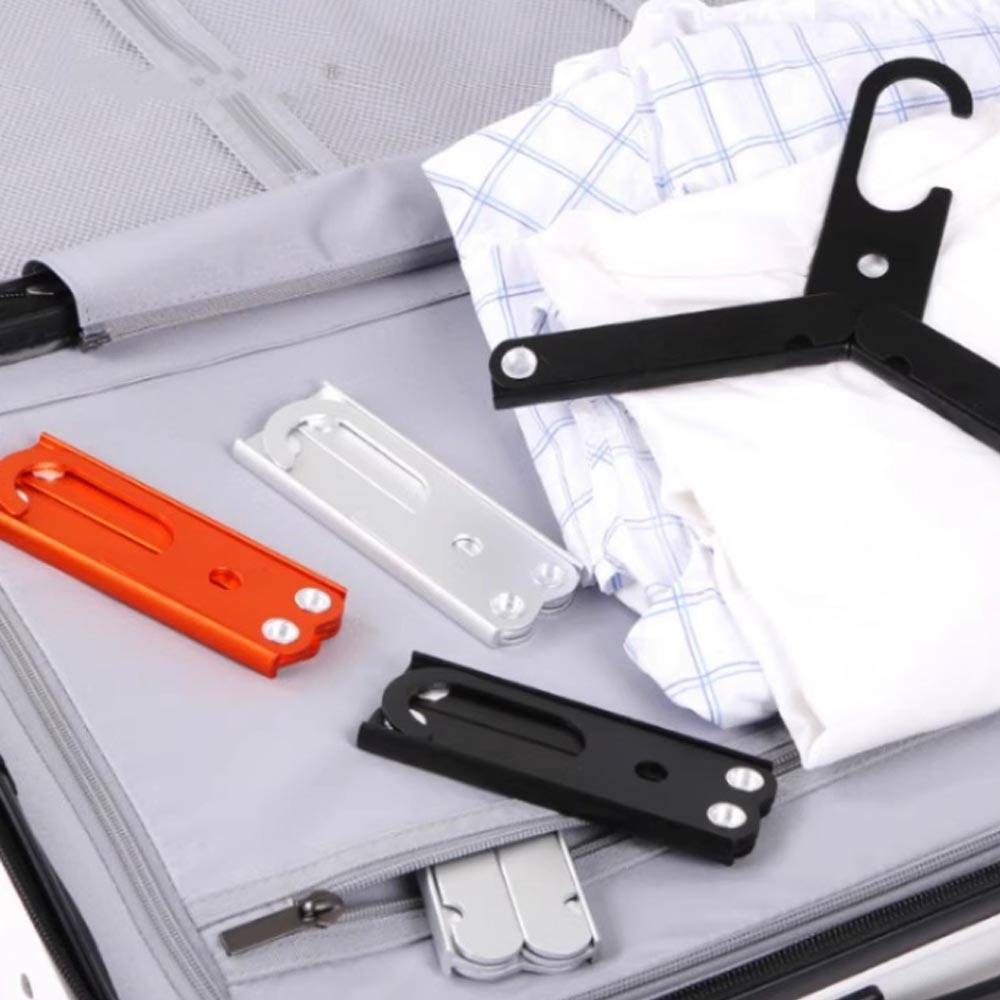 Nahaufnahme eines gepackten Koffers mit gefalteter Kleidung und mehreren Kleiderbügel-Aufsätzen in verschiedenen Farben, was auf Reisepacking oder Garderobe-Organisation hindeutet.