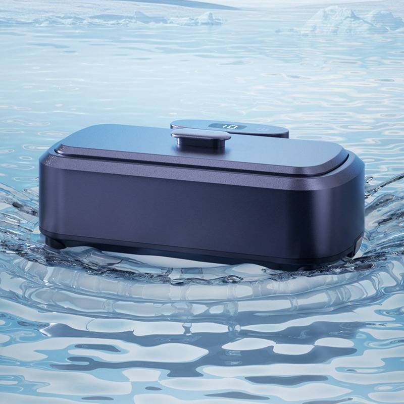Ein kompaktes dunkelblau schwebendes Gerät, wahrscheinlich ein wasserdichter Lautsprecher oder Gadget, sitzt auf kräuselndem Wasser in einer hellblauen Außenszenerie.