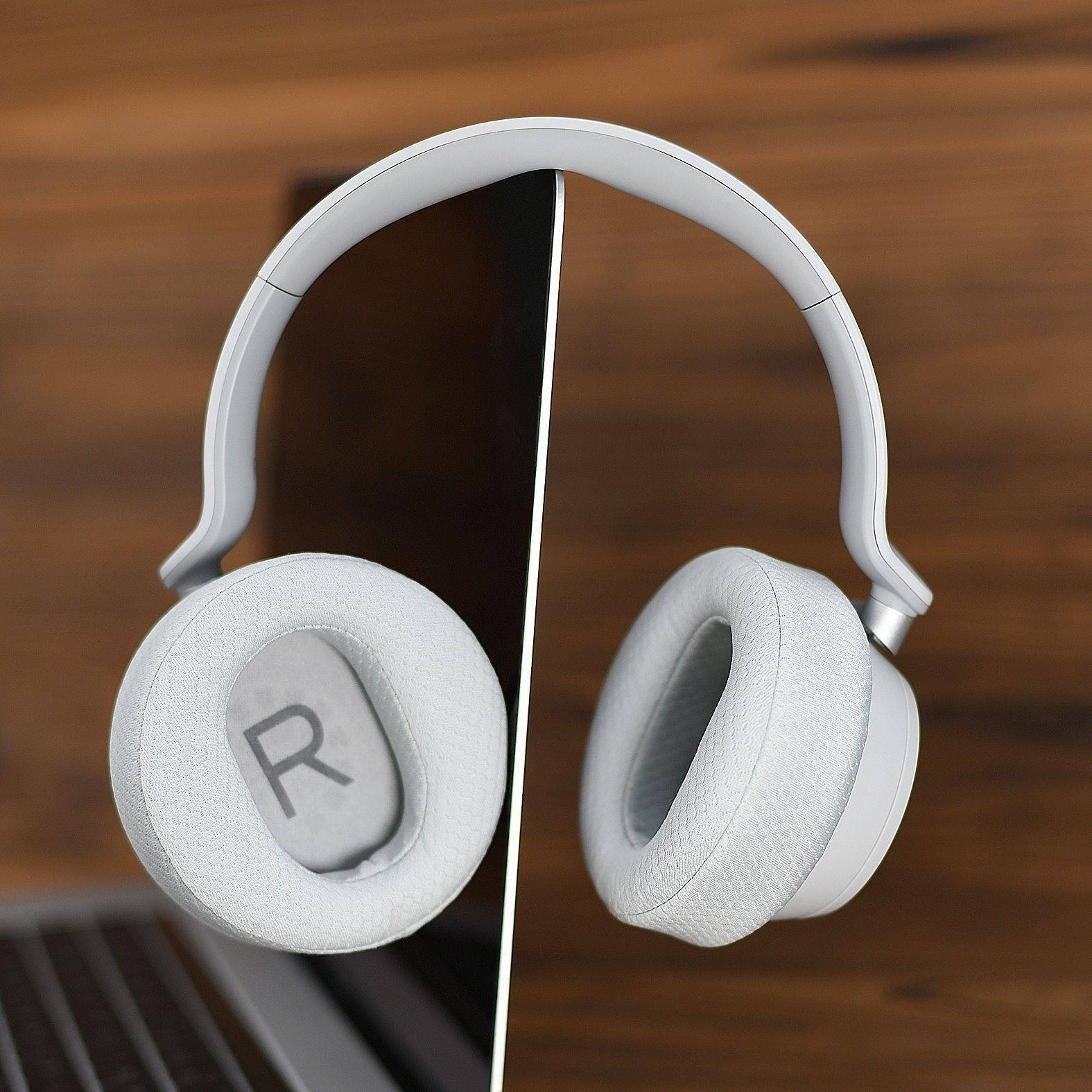 Weiße Over-Ear-Kopfhörer mit Spalteffekt, vor einem Holzhintergrund präsentiert.