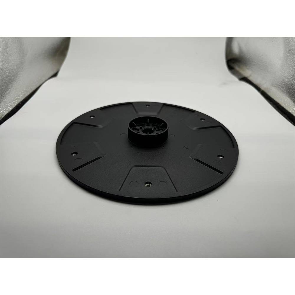 Schwarze kreisförmige Montagebasis mit erhöhtem Mittelstecker, dargestellt auf einer weißen Oberfläche mit reflektierenden Seitenpaneelen drumherum.