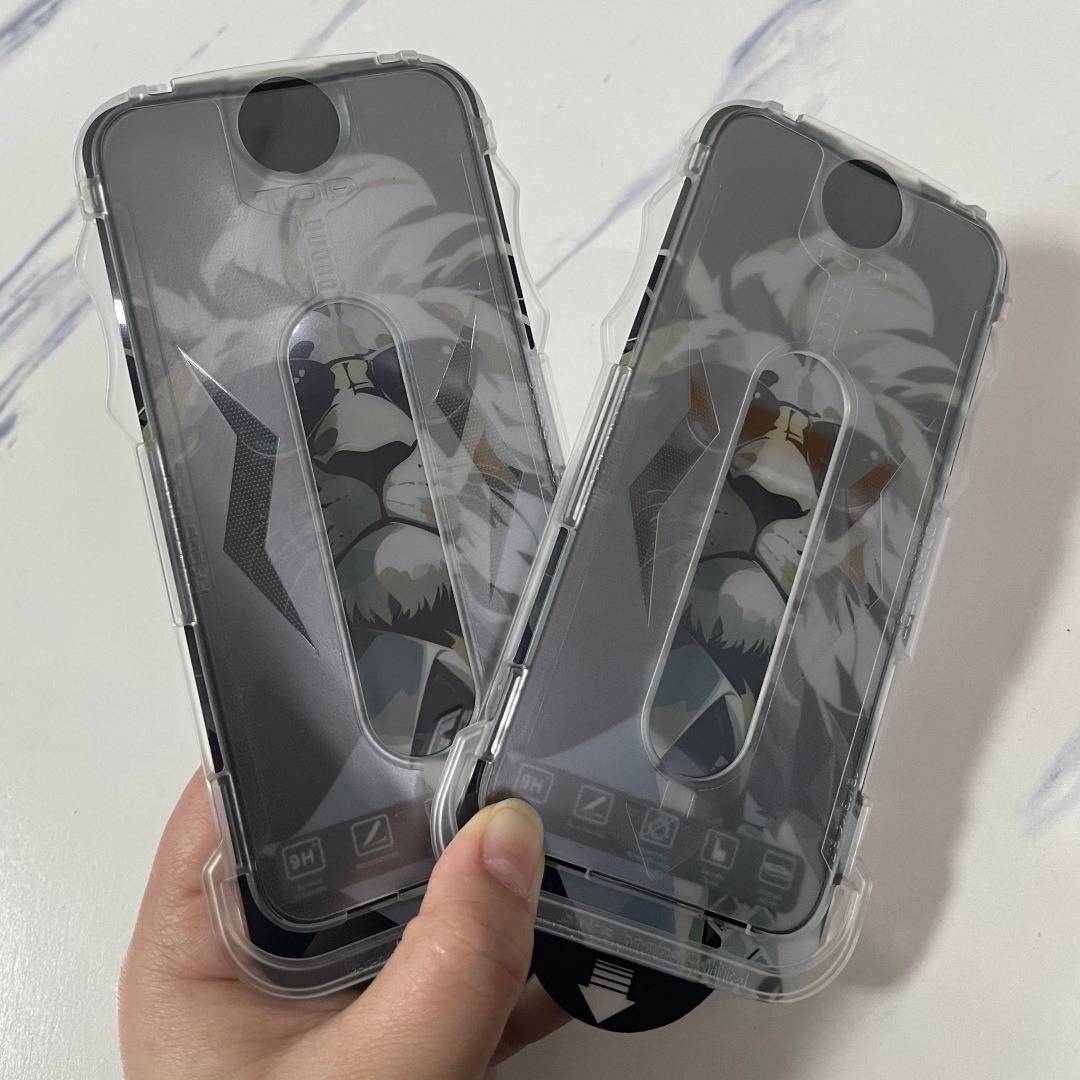 Zwei durchsichtige Smartphone-Hüllen mit reflektierenden schwarzen Einsätzen und floralen Grafiken, die in einer Hand gegen einen weißen Hintergrund gehalten werden.