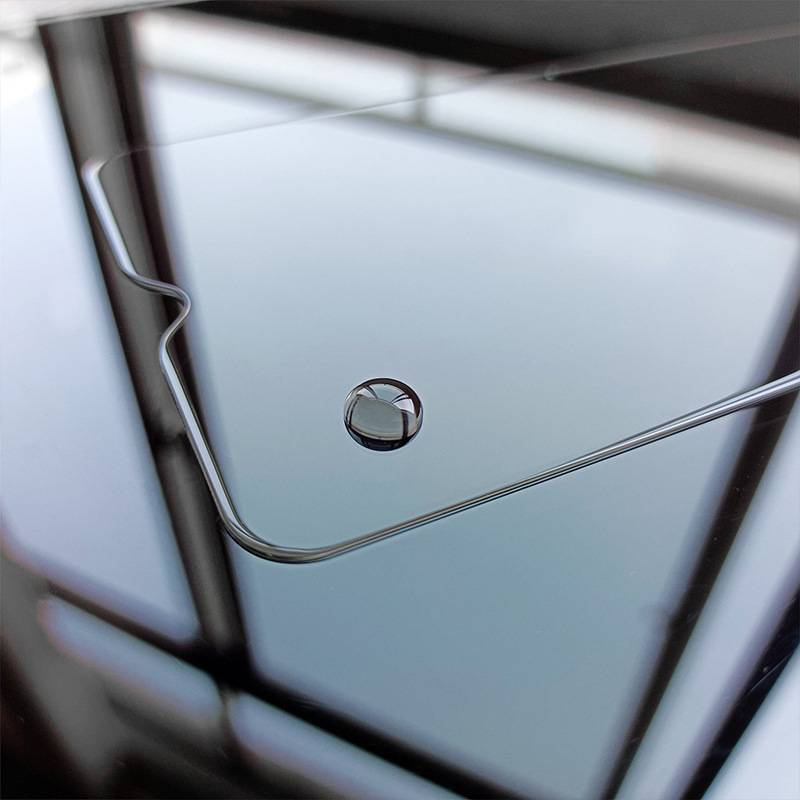 Nahaufnahme eines Laptop-Touchpads mit einem zentrierten kreisförmigen Fingerabdrucksensor und einer silbernen Kante, die nahegelegene Fensterrahmen widerspiegelt.