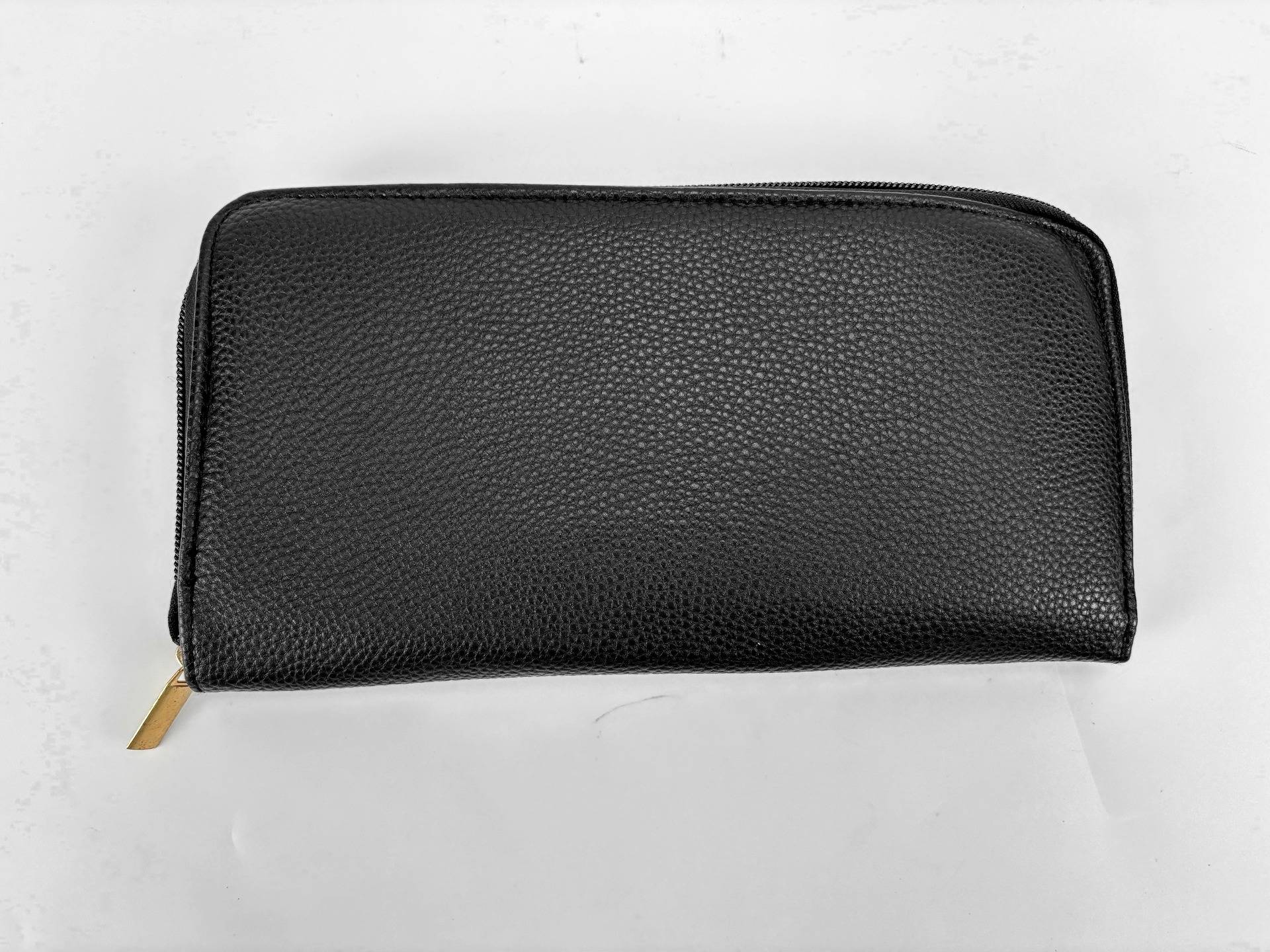 Schwarze Brieftasche oder Clutch-Geldbörse aus Leder mit Reißverschluss, geschlossen auf weißem Hintergrund gezeigt, mit sichtbarem goldenem Reißverschluss-Schieber unten links.