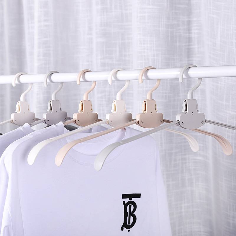 Weiße T-Shirts hängen auf mehreren Pastellkleiderbügeln an einem Kleiderständer, wobei das schwarze „TB