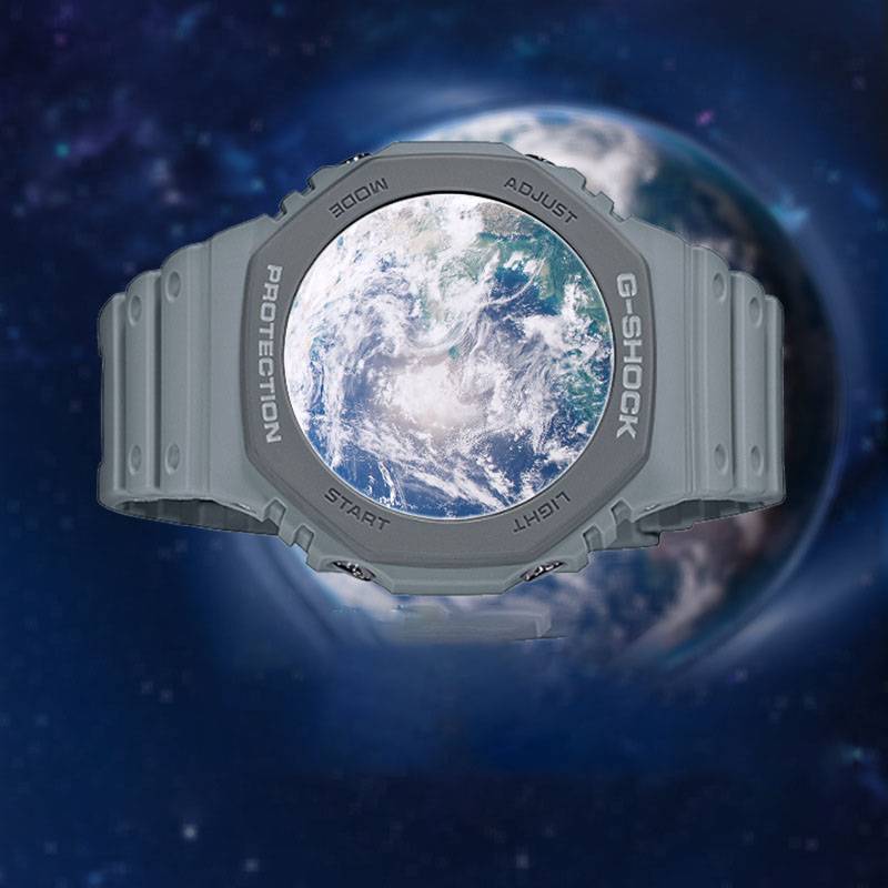 Graue G-Shock-Uhr mit der Erde auf ihrem runden Zifferblatt, schwebend vor einem dunklen, sternenbedeckten Weltraum-Hintergrund.