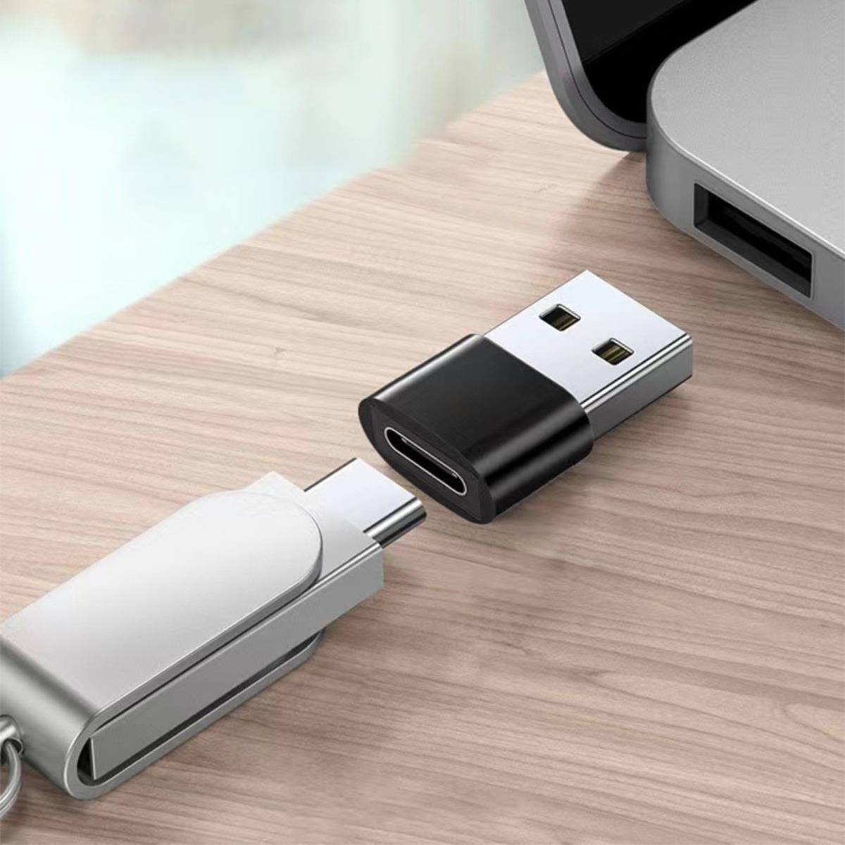 Nahaufnahme von zwei USB-Sticks, die über einen USB-C-Adapter auf einem Holzschreibtisch verbunden werden.