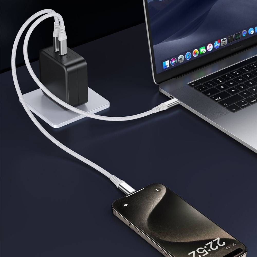Ein Laptop lädt ein schwarzes Z2:2-Smartphone über ein weißes Kabel von einem Wandladegerät auf einem Schreibtisch auf.