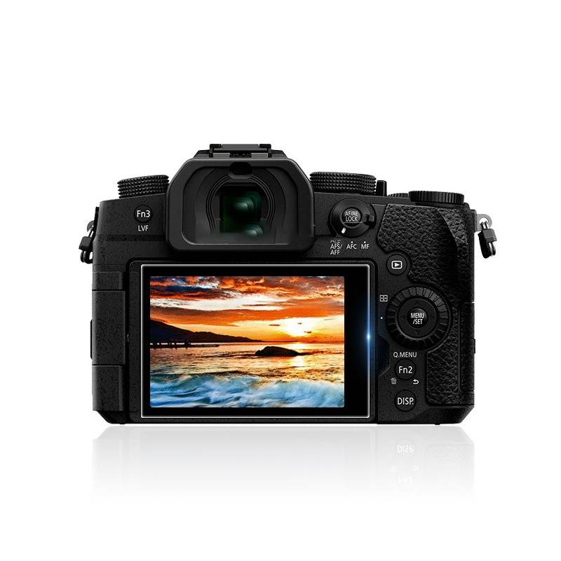 Rückansicht einer schwarzen Digitalkamera mit ihrem rückseitigen LCD-Display, auf dem ein Sonnenuntergangs-Seelandschaftsfoto angezeigt wird.