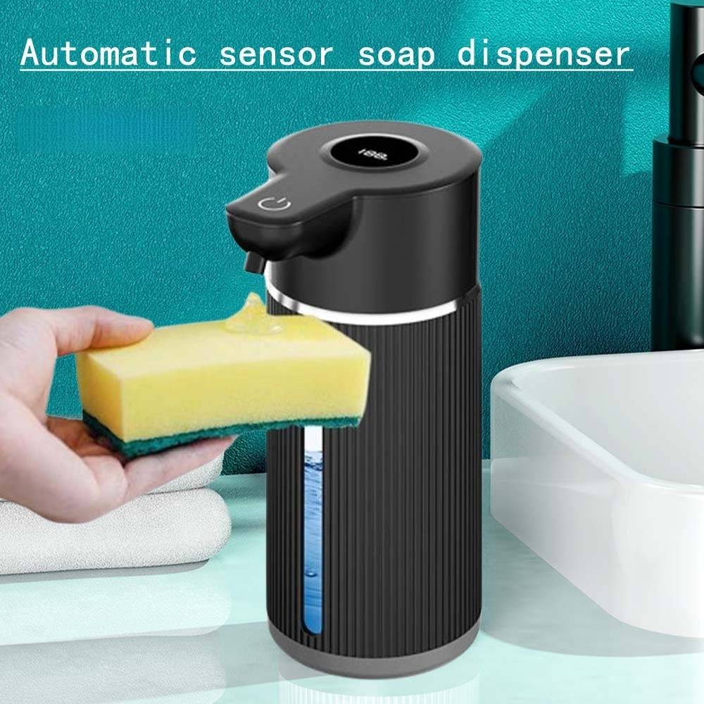 Hand, die Seife auf einen Schwamm neben einem schwarzen automatischen Sensor-Seifenspender mit der Aufschrift 
