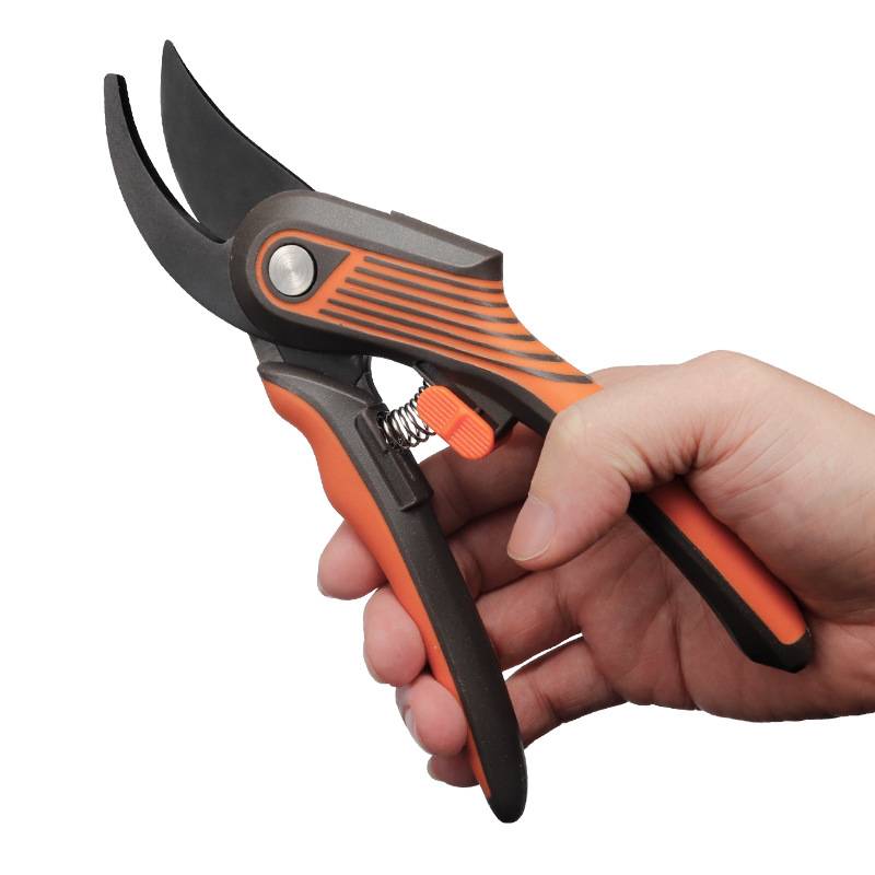 Hand hält orange-schwarze Gartenschere mit gebogenen Klingen, geöffnet und bereit zum Schneiden.