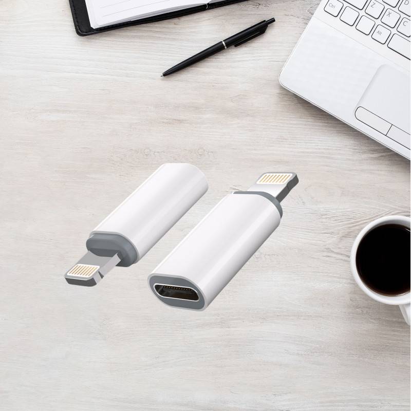 Zwei weiße USB-C-Adapter-Dongles auf einem Schreibtisch neben einem Laptop, einem Stift, einem Notizbuch und einer Kaffeetasse.