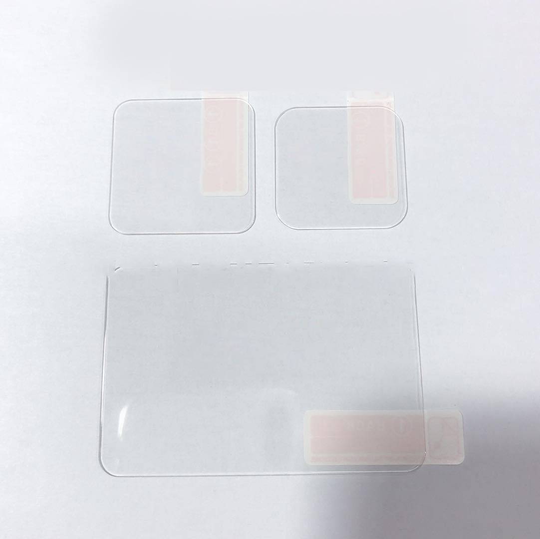 Drei transparente Klebfolienteile in verschiedenen Größen auf weißem Hintergrund, wahrscheinlich Schutzfolien-Patches oder Musterdekale.