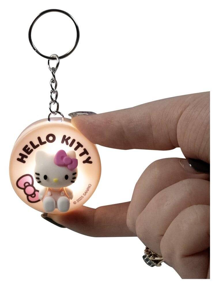 Hand hält einen Hello-Kitty-Schlüsselanhänger mit einem runden leuchtenden Charm und Metallring, der die Figur und den Text „HELLO KITTY