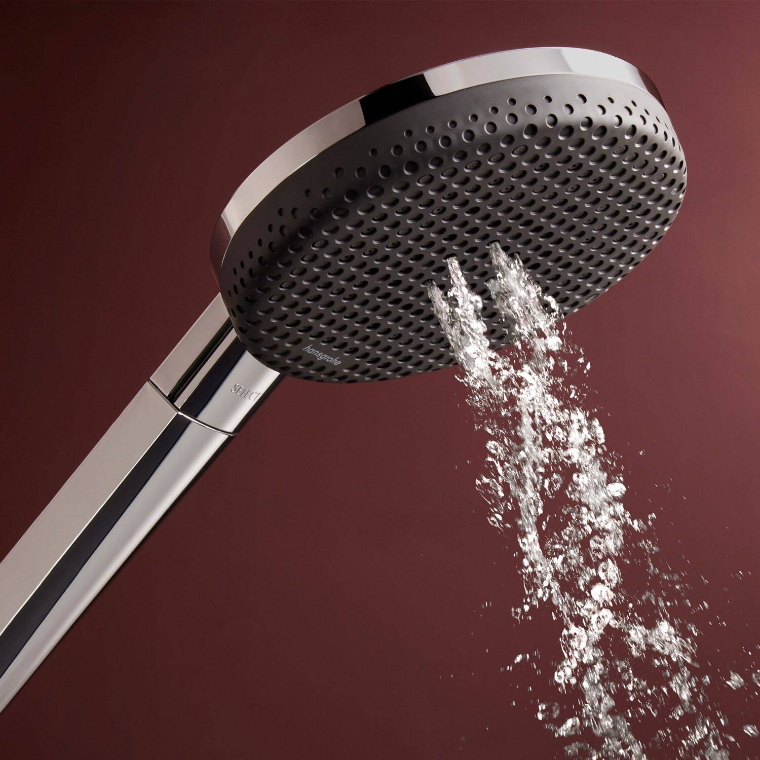 Chrom-Handbrause sprüht Wasser vor dunkelrotem Hintergrund.