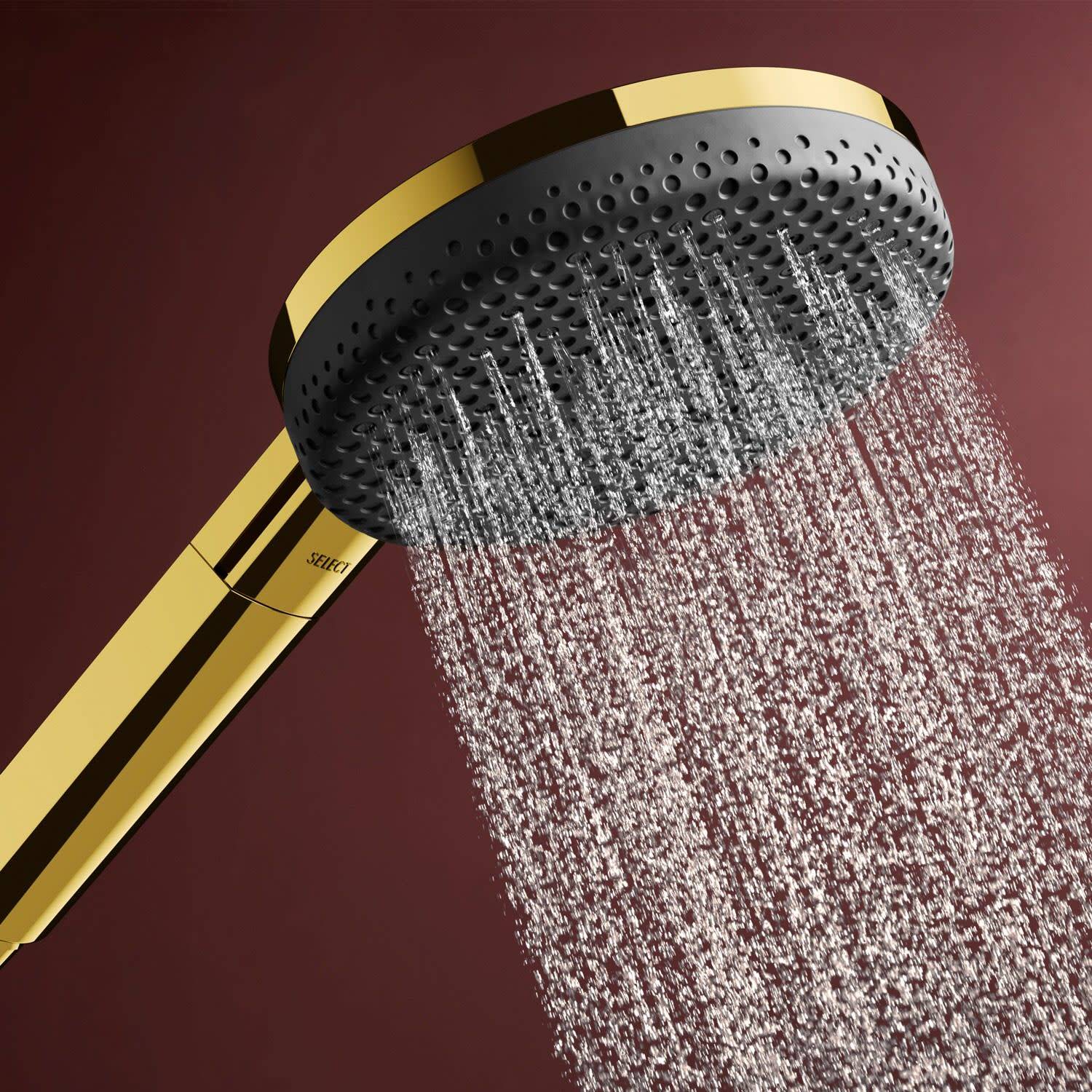 Goldener tragbarer Duschkopf, der Wasser auf dunkelrotem Hintergrund sprüht.
