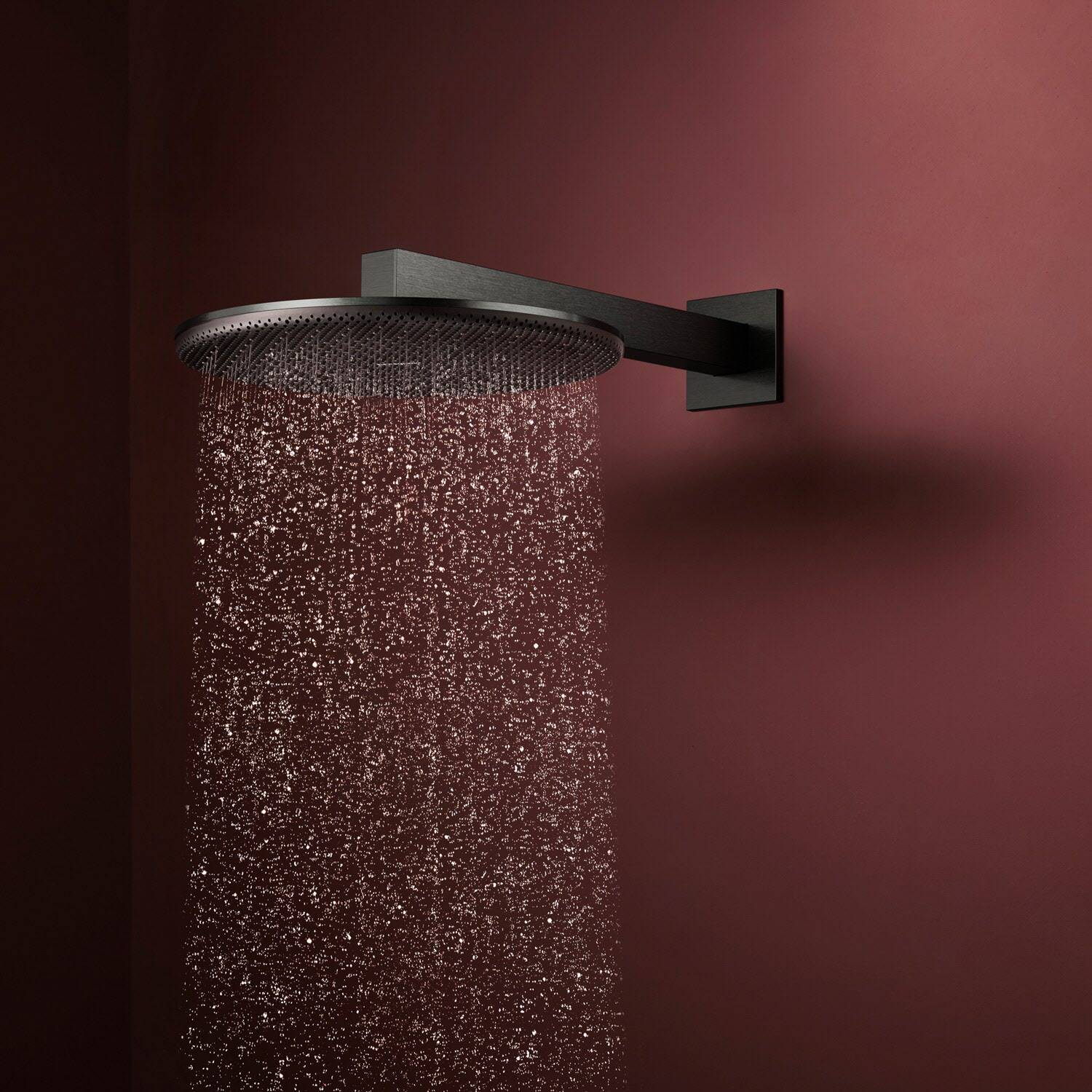 Moderner schwarz wandmontierter Duschkopf sprüht Wasser gegen eine dunkelrote Badezimmerwand.