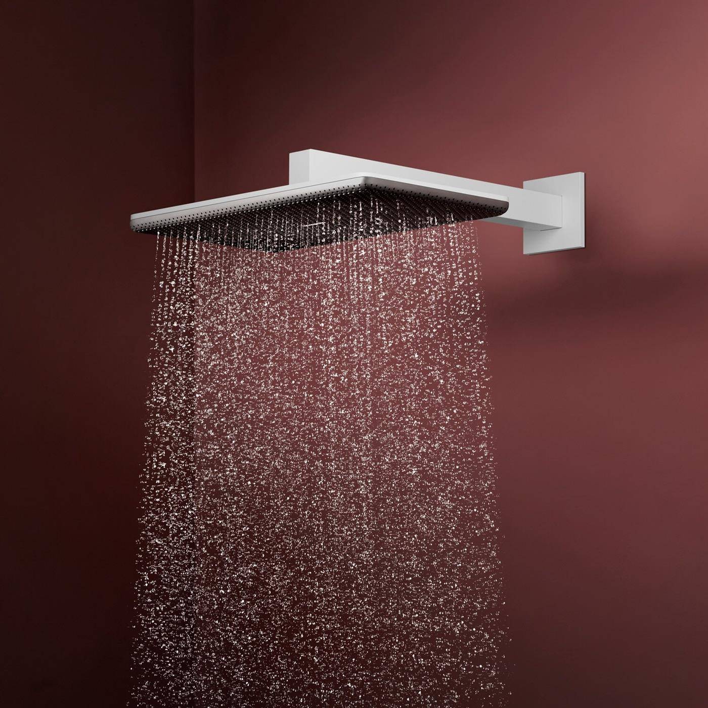 Moderner quadratischer Regenduschkopf an der Wand montiert, der Wasser gegen einen dunkelroten Hintergrund sprüht.