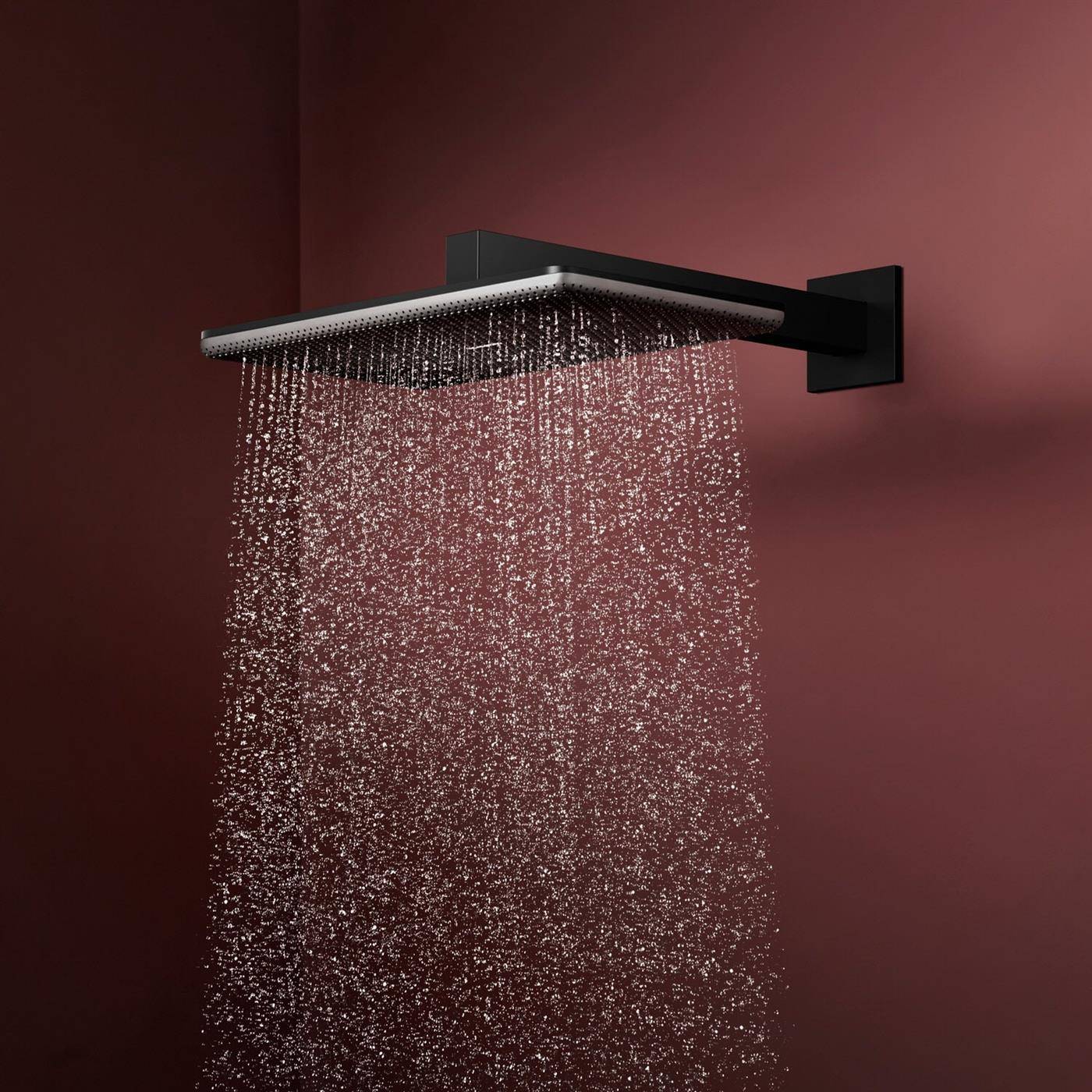 Moderner, wandmontierter Regenduschkopf, der Wasser gegen einen kastanienbraun gefärbten Hintergrund sprüht.
