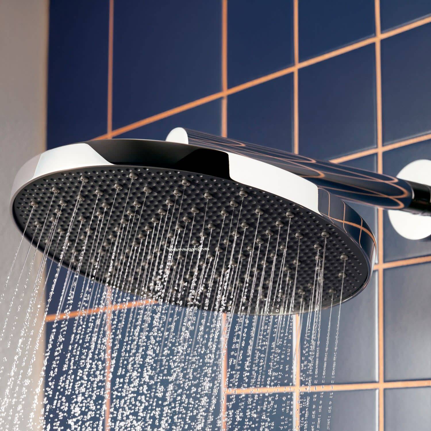 Ein großer moderner Regenduschkopf, der Wasser gegen eine gekachelte Badezimmerwand sprüht.