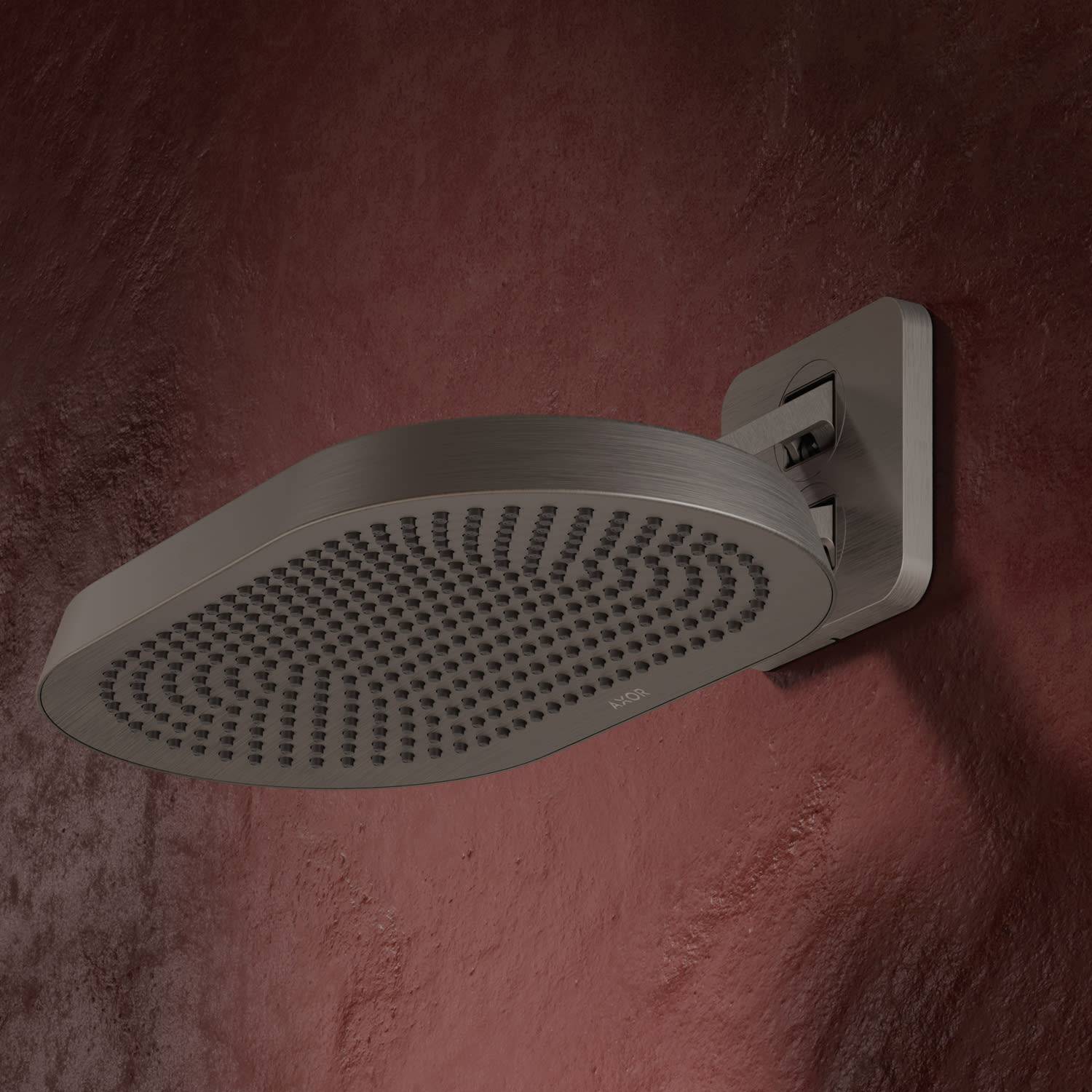 Nahaufnahme eines modernen, an der Wand montierten Regenbrausekopfes aus Edelmetall mit gebürsteter Oberfläche vor einer roten strukturierten Wand.