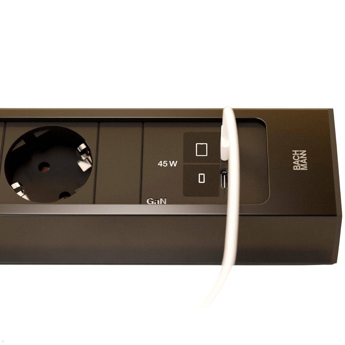 Schwarze Steckdosenleiste mit einer runden Steckdose und USB-Anschlüssen, mit der Aufschrift 45 W GaN und Bachmann, mit einem weißen Kabel angesteckt.