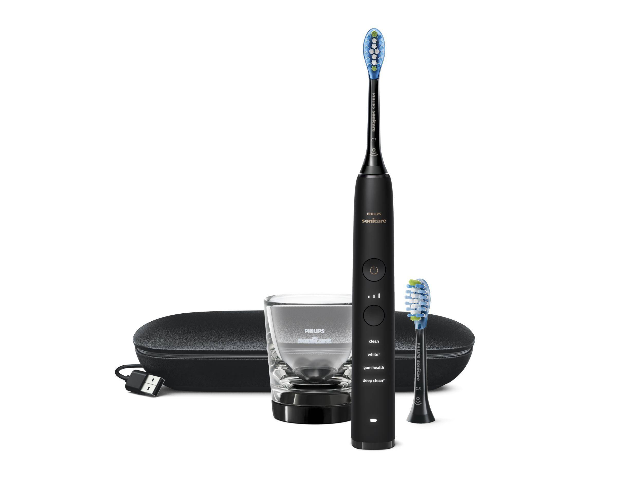 Philips Sonicare Elektrozahnbürsten-Set mit Griff, zwei Bürstenköpfen, Ladeglas und Reiseetui auf weißem Hintergrund.