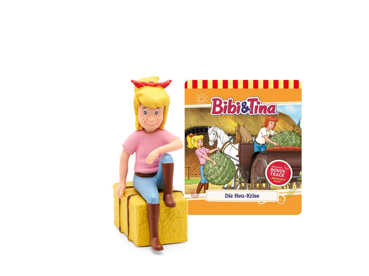 Eine Bibi & Tina-Figur, die auf einem Heuballen sitzt, neben dem Buchcover „Die Heu-Krise