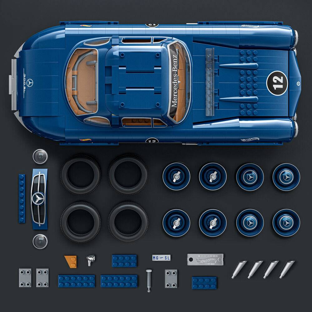 Draufsicht eines blauen Mercedes-Benz-Rennwagen-Modellbausatzes mit ausgebreiteten Teilen zur Montage, einschließlich Karosserieschale, Räder, Abziehbilder und kleiner Zubehörteile.