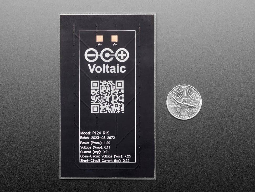 Ein Voltaic-Solarpanel-Etikett mit QR-Code und Spezifikationen neben einer Münze zum Größenvergleich.