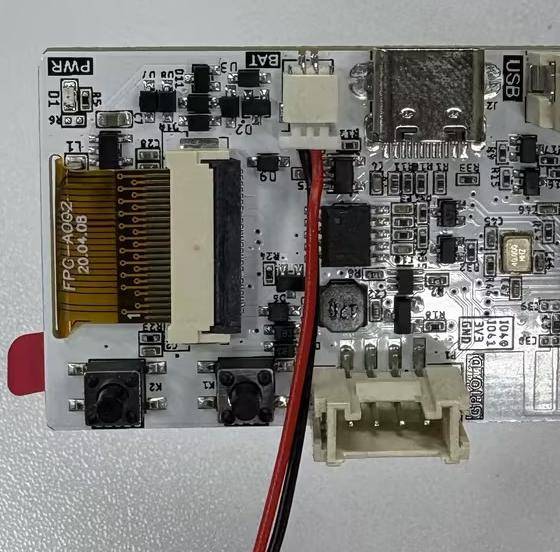 Nahaufnahme einer kleinen elektronischen Leiterplatte mit einem Flachbandkabel-Anschluss, USB-Anschluss, Drahtleitungen und mehreren Tasten und Komponenten.