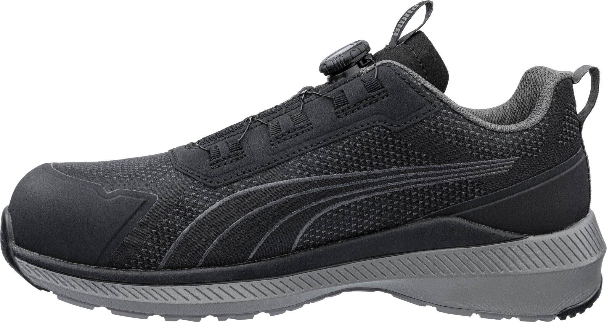 Schwarzer Sportschuh mit grauer Sohle und strukturiertem Obermaterial, in Seitenansicht auf weißem Hintergrund dargestellt.