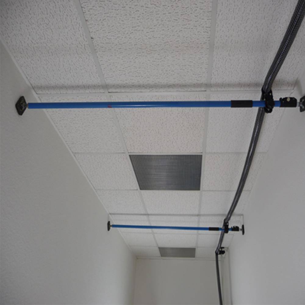 Blaue horizontale Stützstangen, die quer durch eine Flurdecke neben einem Kabel oder Rohr montiert sind.