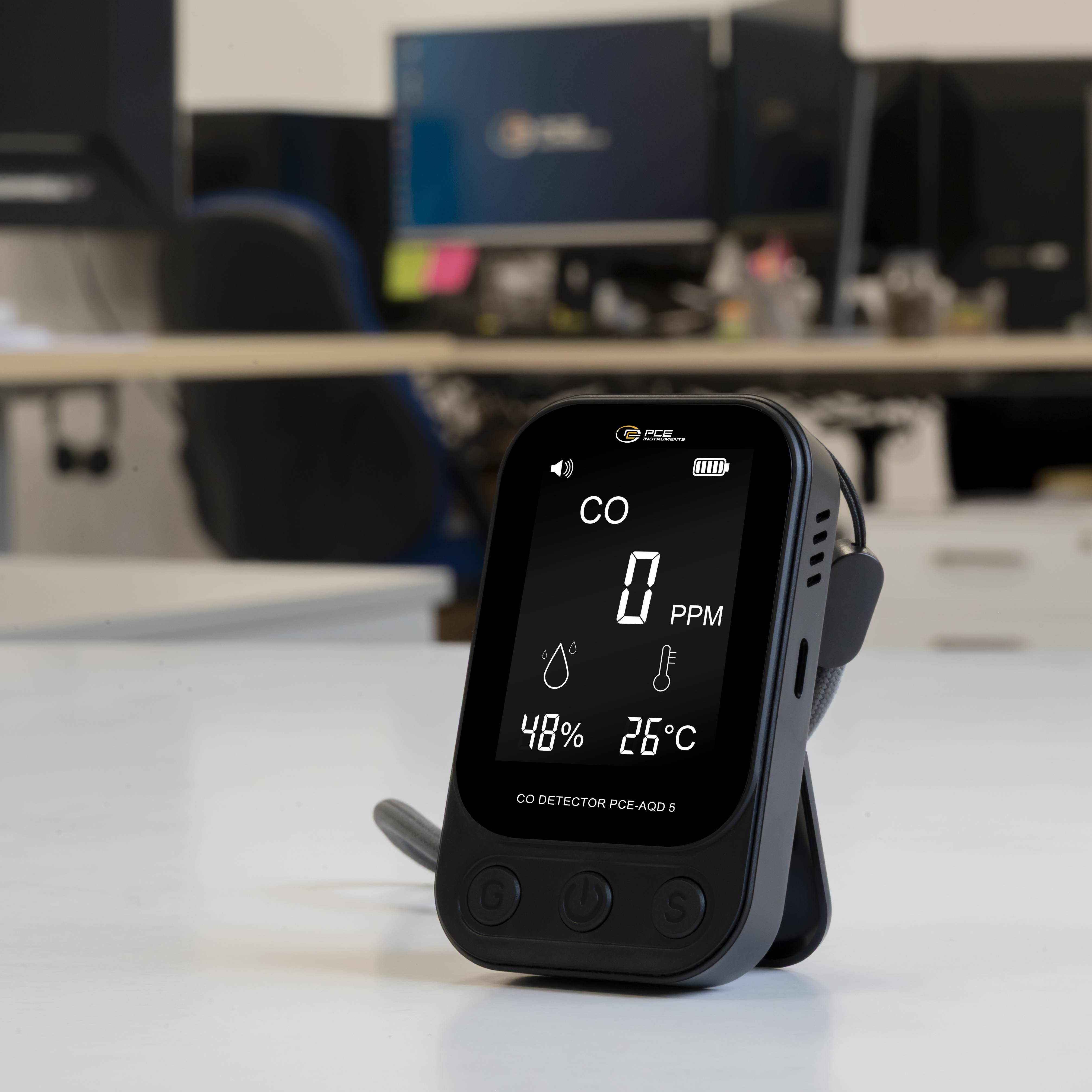 Tragbarer CO-Detektor auf einem Schreibtisch, auf dessen Bildschirm 0 PPM, 48% Luftfeuchte und 26°C angezeigt werden.