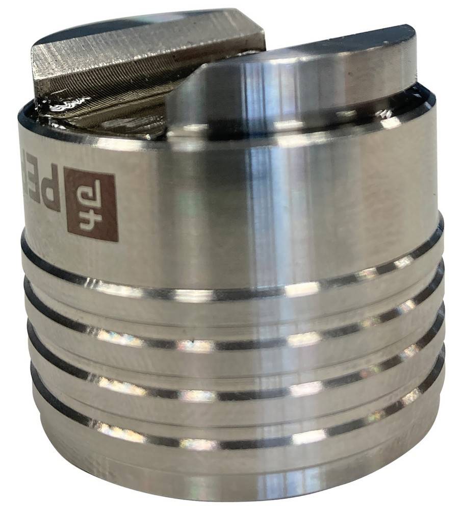 Nahaufnahme einer zylindrischen Metallkomponente mit geschlitzter Oberseite und gerillten Seiten, wahrscheinlich ein bearbeitetes Werkzeug oder Maschinenteil.