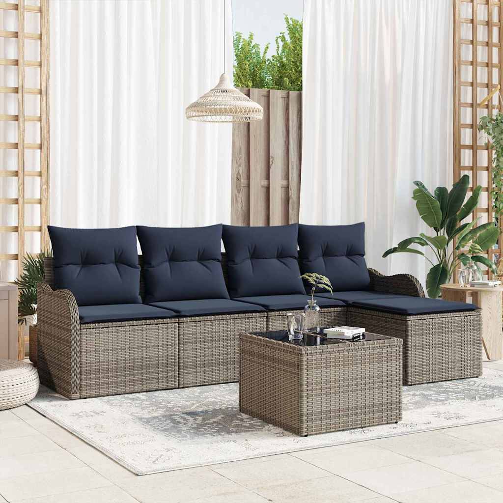 Outdoor-Terrassensektionalsofa mit marineblauen Kissen, passendem geflochtenem Couchtisch im Ottomanstil und Pflanzen in einem hellen verglasten Sitzbereich.