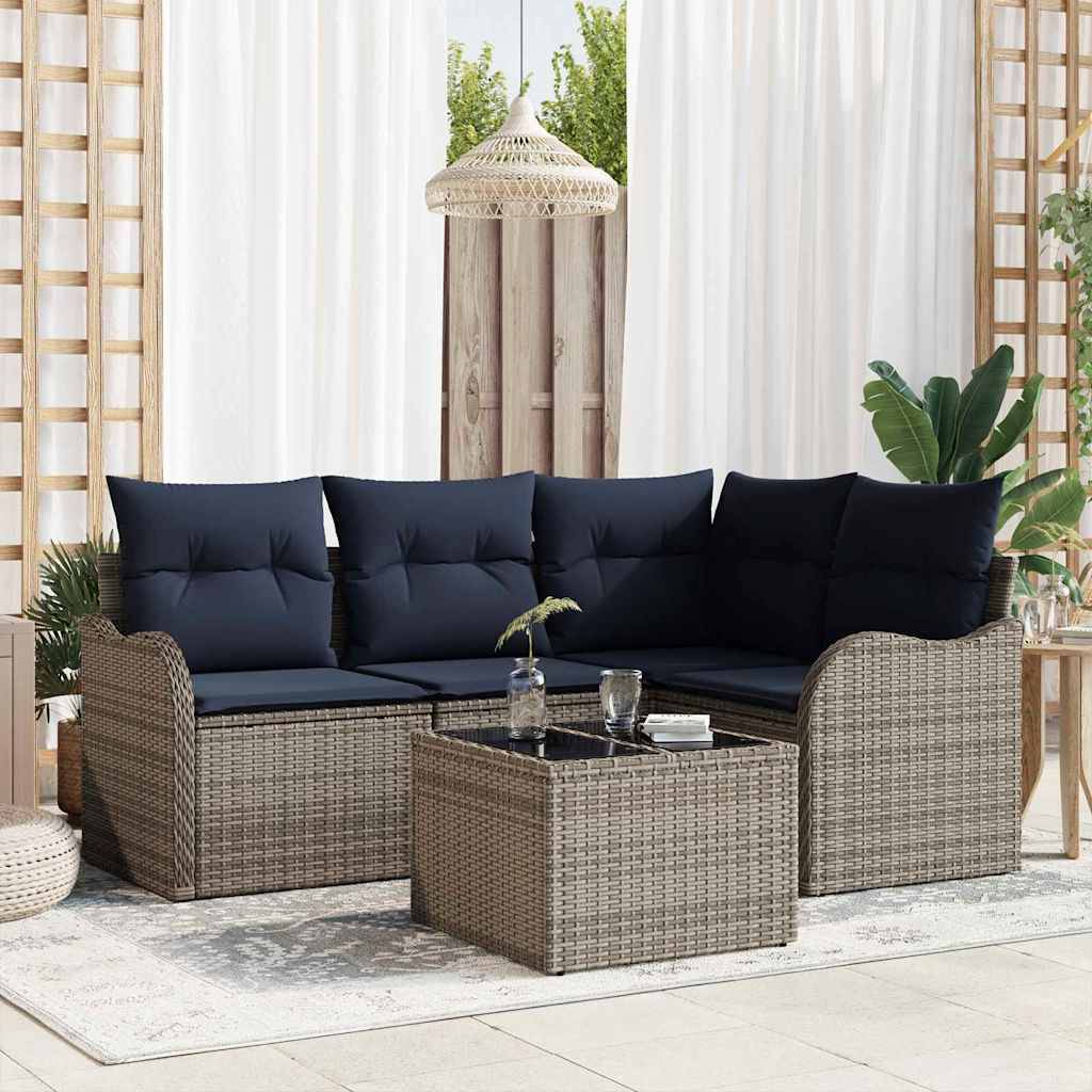 Outdoor-Rattanpolstermöbel-Set mit dunklen Kissen, passendem Couchtisch und Pflanzen auf einem hellen Terrasssenteppich.
