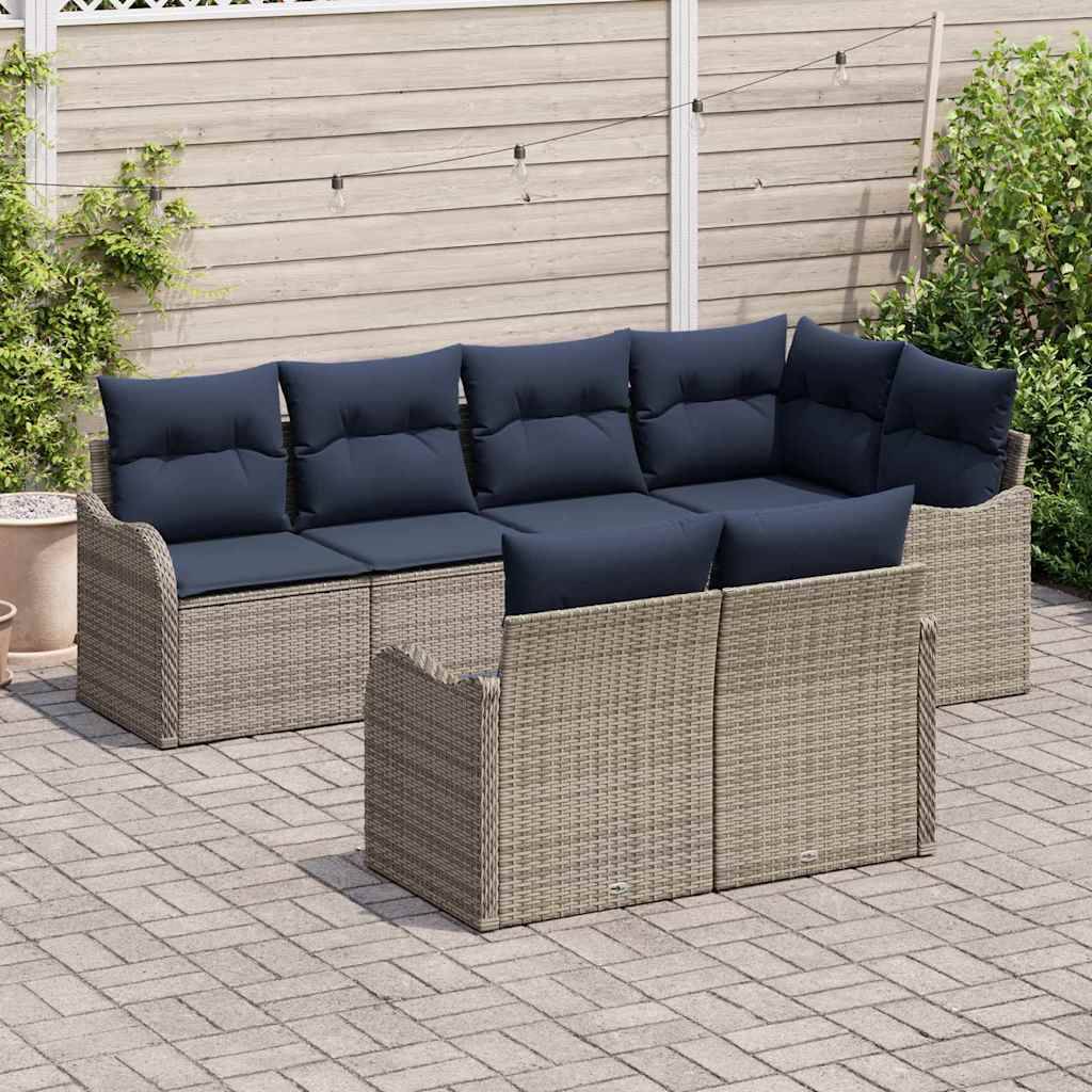 Outdoor-Rattanecksofa-Set mit dunklen Kissen auf einer gepflasterten Terrasse angeordnet, einschließlich eines passenden Ottomans oder Stuhls davor.