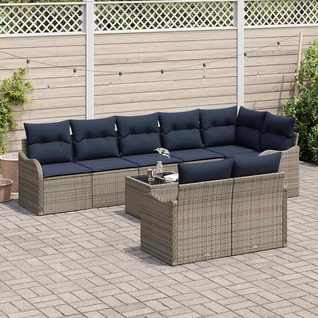 Outdoor-Terrassenmöbel-Set mit einem Rattan-Ecksofa, einem Sessel und einem Couchtisch mit dunklen Kissen auf einer gepflasterten Terrasse.