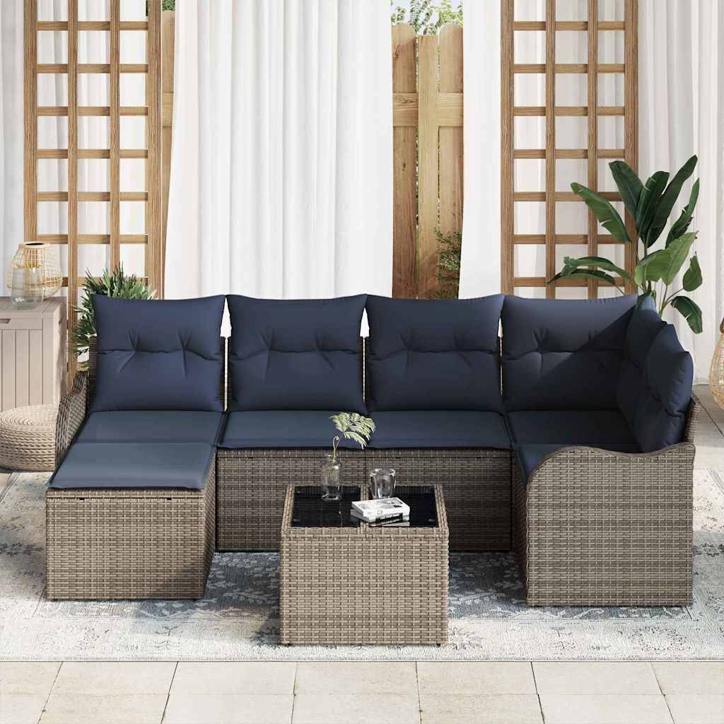 Outdoor-Rattansektionalsofa mit marineblauen Kissen und passendem Ottoman-Couchtisch auf einer Terrasse, umrahmt von Pflanzen und Vorhängen.