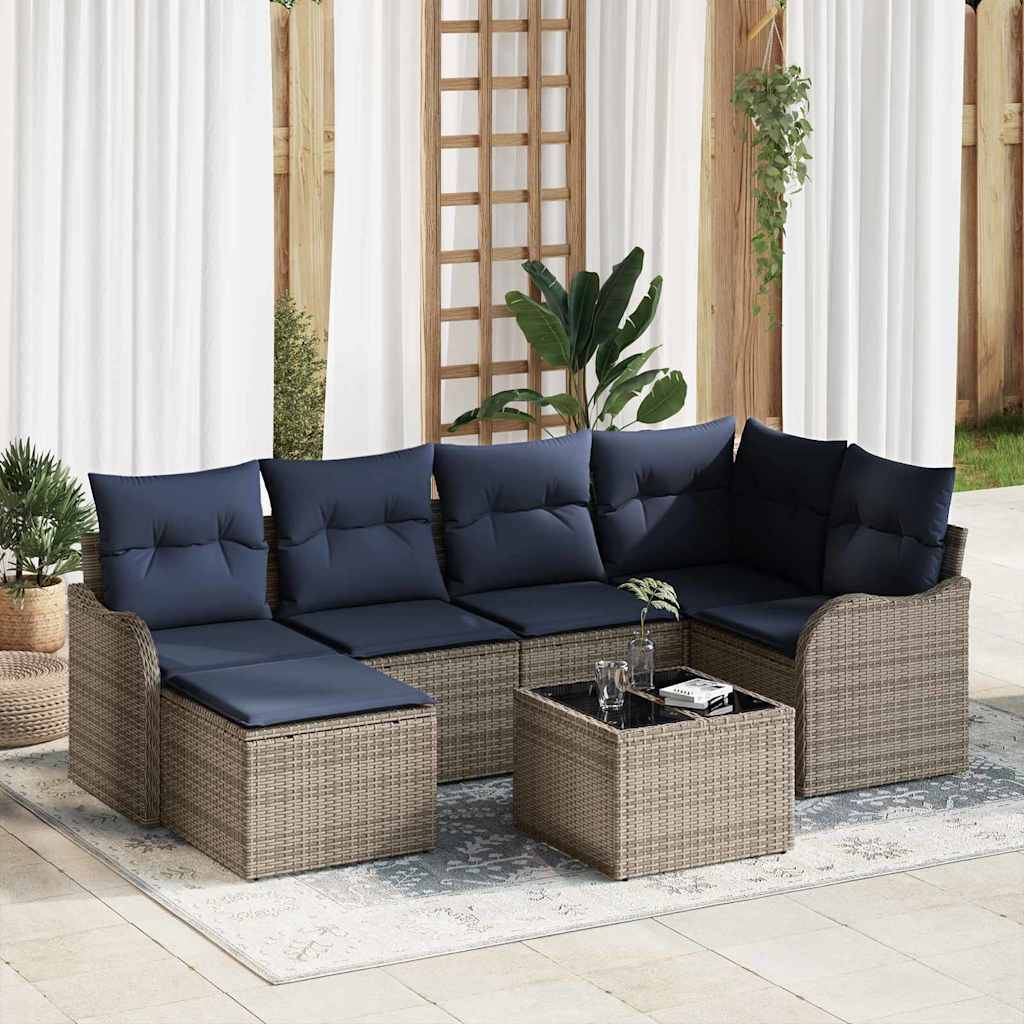 Outdoor-Rattanecksofa mit marineblauen Kissen und passendem Couchtisch auf einer Terrasse, gestylt mit Pflanzen und Vorhängen.
