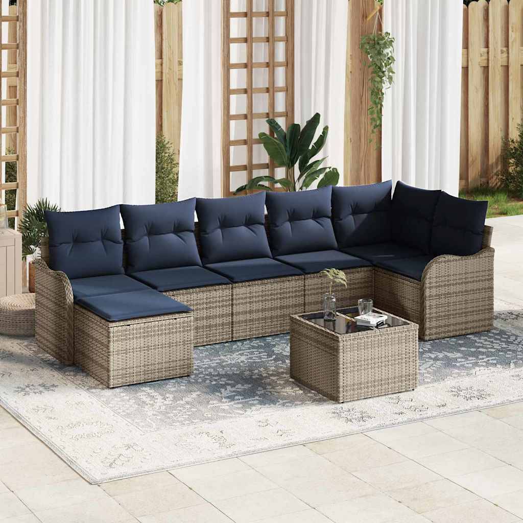 Outdoor-Rattansitzgruppe mit marine Kissen, passendem Couchtisch und gemustertem Teppich auf einer Terrasse.