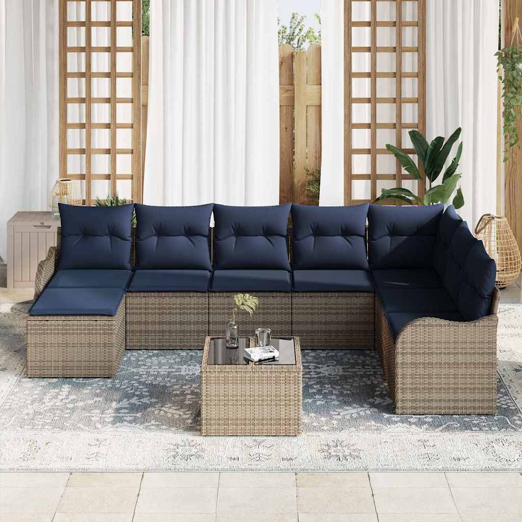 Outdoor-Sitzkombination mit marineblauen Kissen um einen kleinen Flechtwerk-Couchtisch auf einem gemusterten Teppich, angeordnet auf einer hellen Terrasse oder in einem Wintergarten.