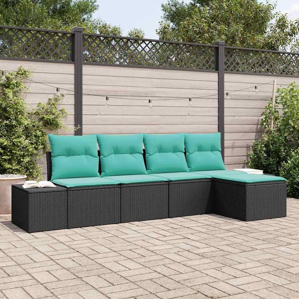 Outdoor-Loungensektion mit schwarzem gewebtem Rahmen und türkisfarbenen Kissen, angeordnet gegen eine Gartenmauer mit Zaun und Lichterketten.