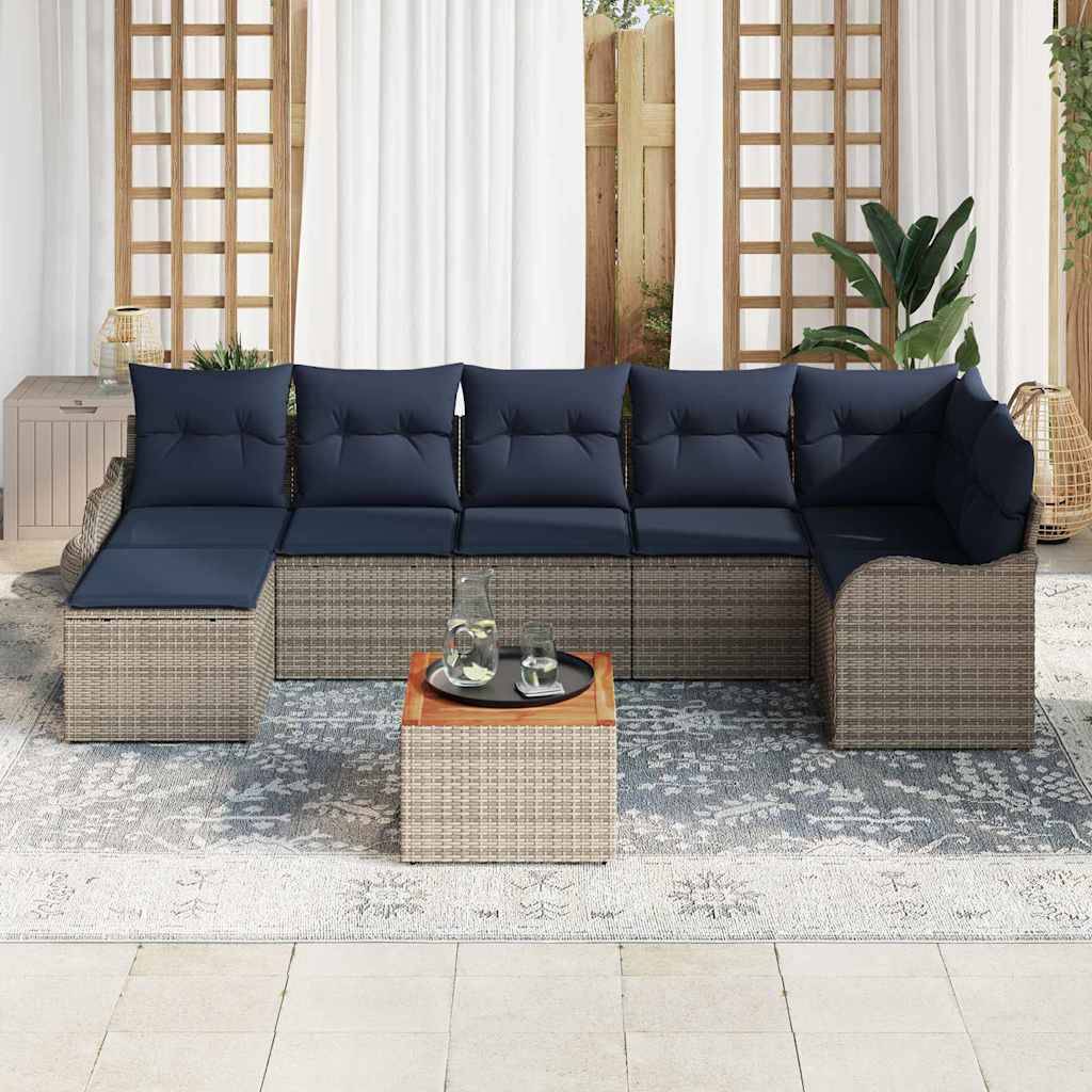 Patio-Ecksofa mit marineblauen Kissen und Rattan-Rahmen, angeordnet um einen kleinen passenden Couchtisch auf einem gemusterten Outdoor-Teppich.