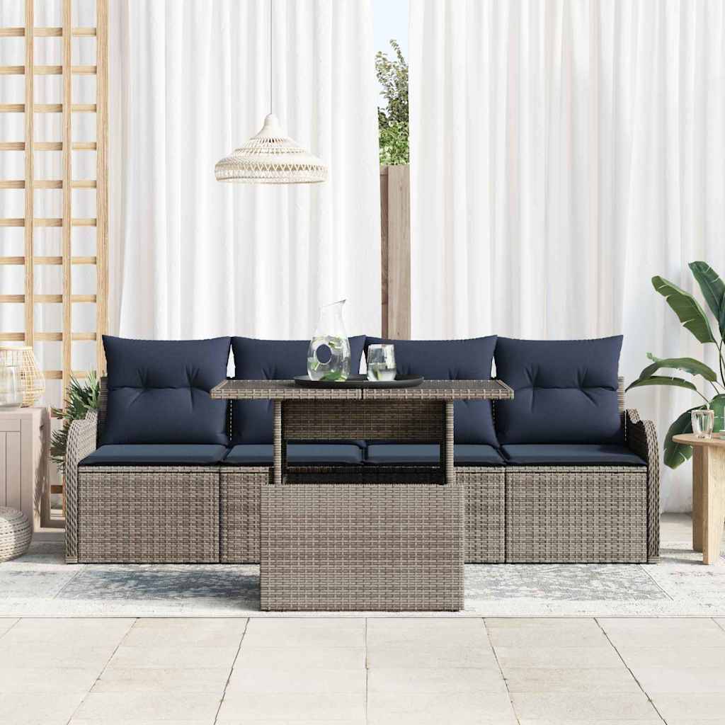Outdoor-Rattansofagarnitur mit marineblauen Kissen und passendem Couchtisch auf einer Terrasse, gestylt mit Pflanzen und einer Hängelampe.