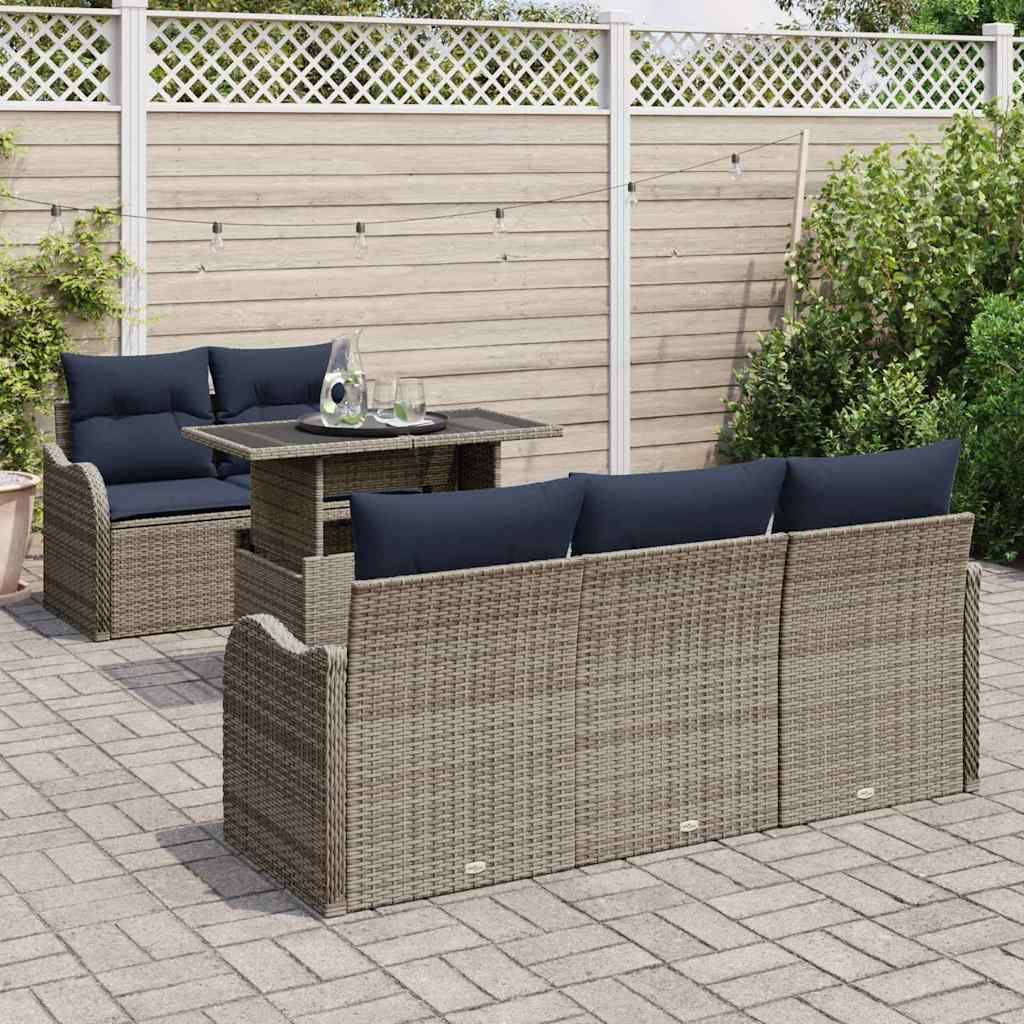 Outdoor-Korbmöbel-Loungeserie mit dunkelblauem Polster und passendem Tisch auf einer gepflasterten Terrasse neben einem Zaun und Sträuchern.